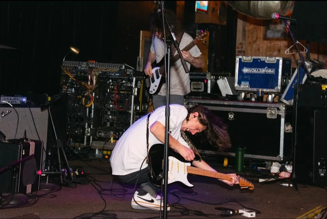 A guitarist crouched at the front of the stage